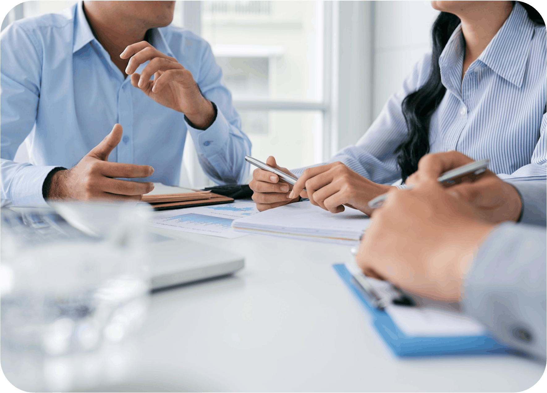 Three professionals at a conference table, planning and making notes.